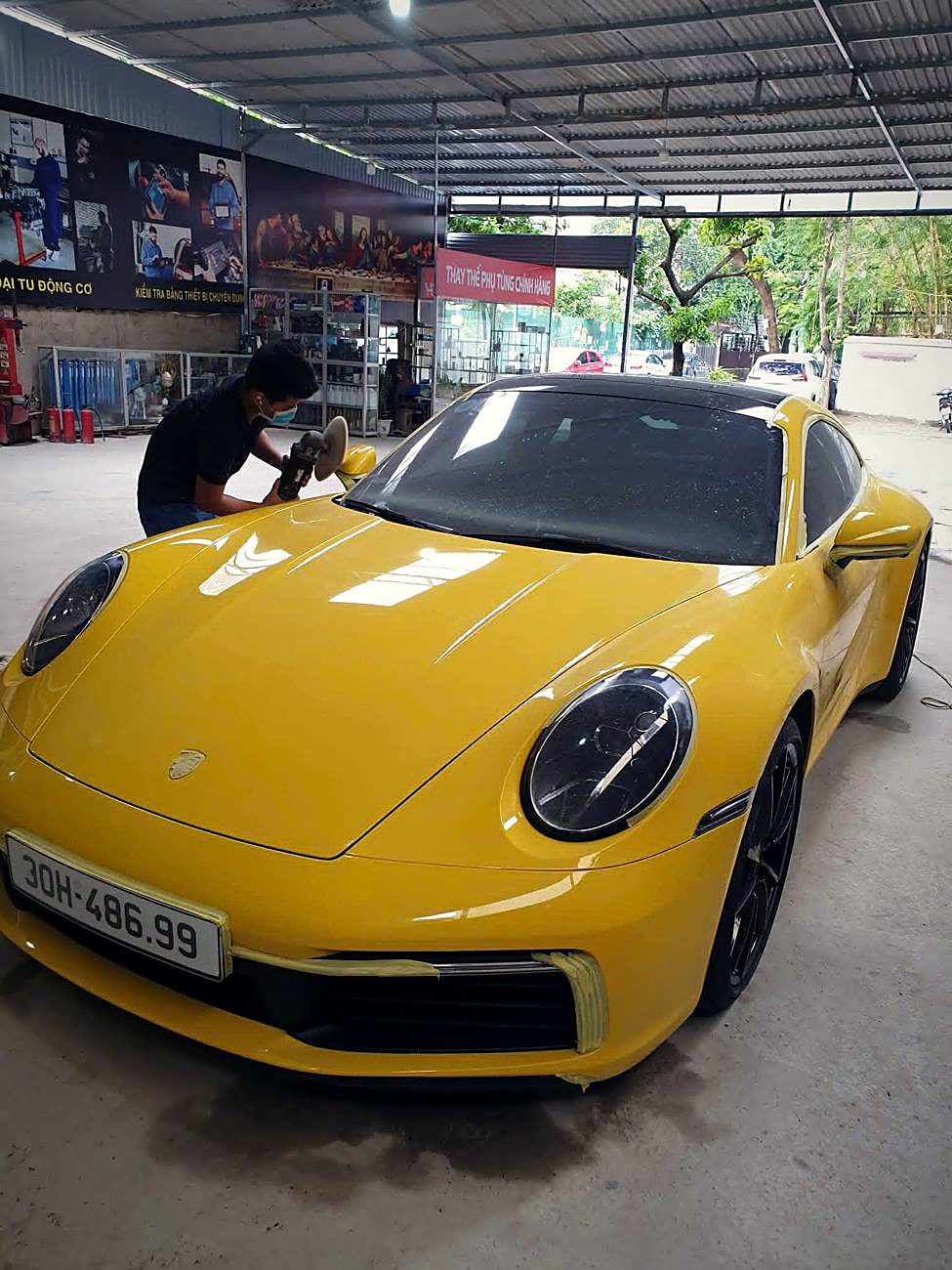 Kỹ thuật viên Thuận Phát chăm sóc Porsche 911 màu vàng trong xưởng